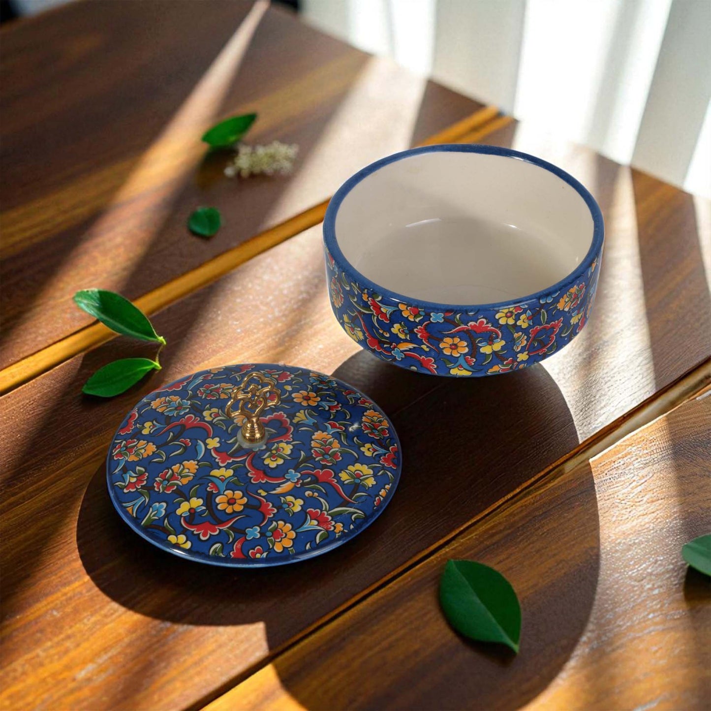 Decorative blue sugar bowl with floral patterns on a wooden surface