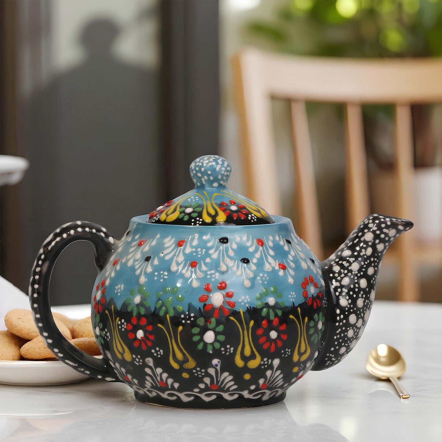 Decorative ceramic teapot with floral patterns on a table.