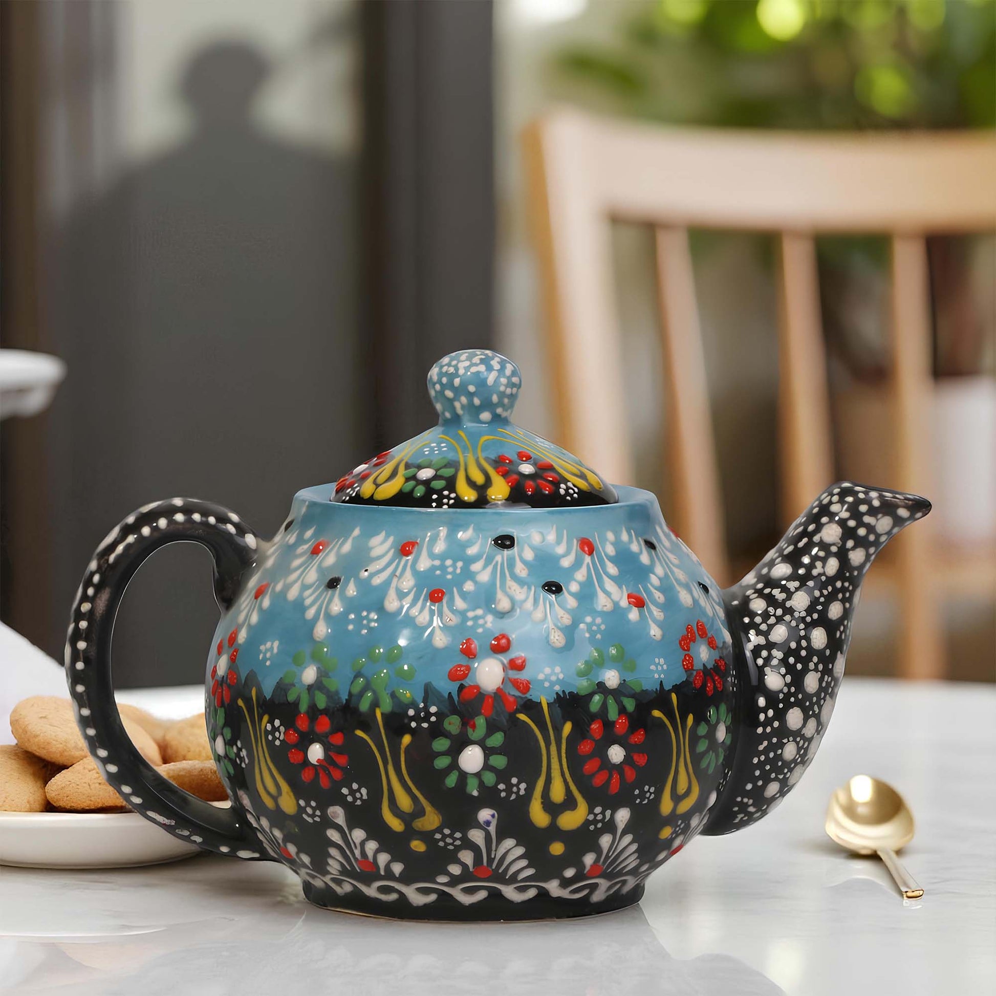 Decorative ceramic teapot with floral patterns on a table.