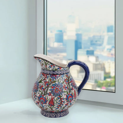 Hand-painted ceramic pitcher with Iznik-inspired tulips, carnations & leaves in red, blue & green. Decorative artisan piece, perfect for display.