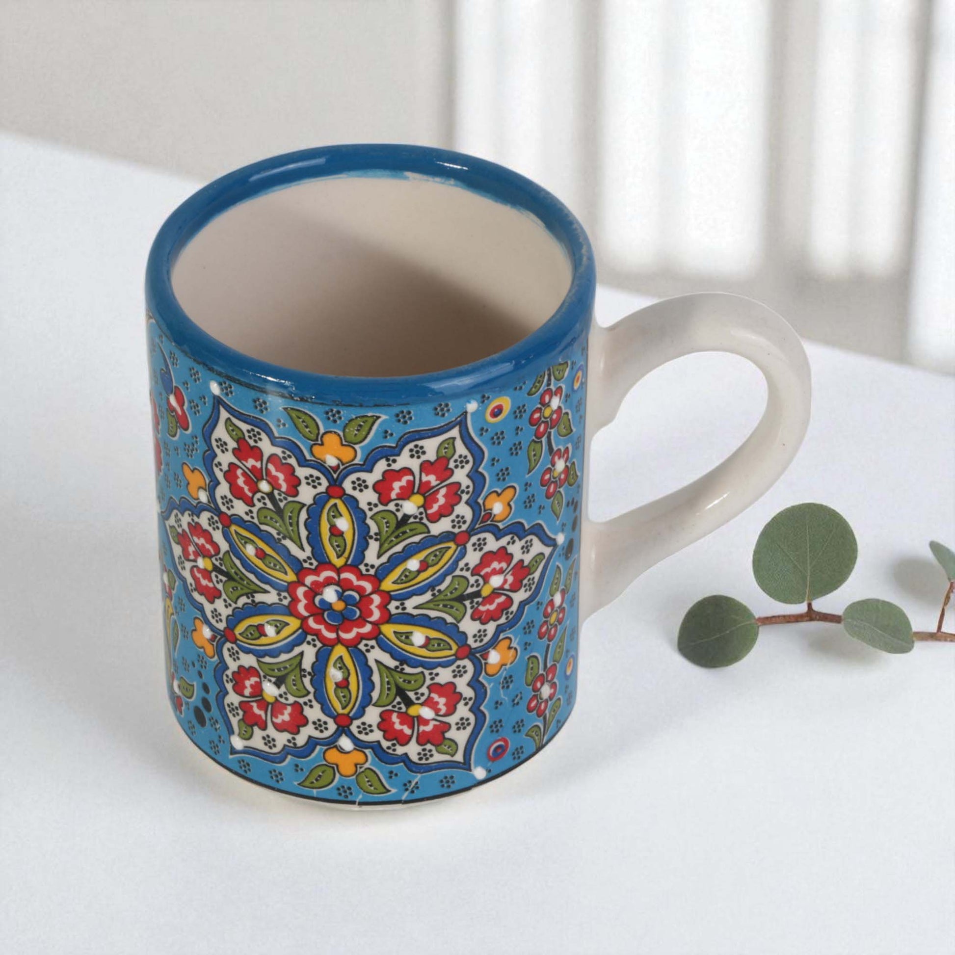 Ceramic coffee mug with colorful floral pattern on a white surface