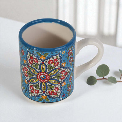 Ceramic coffee mug with colorful floral pattern on a white surface