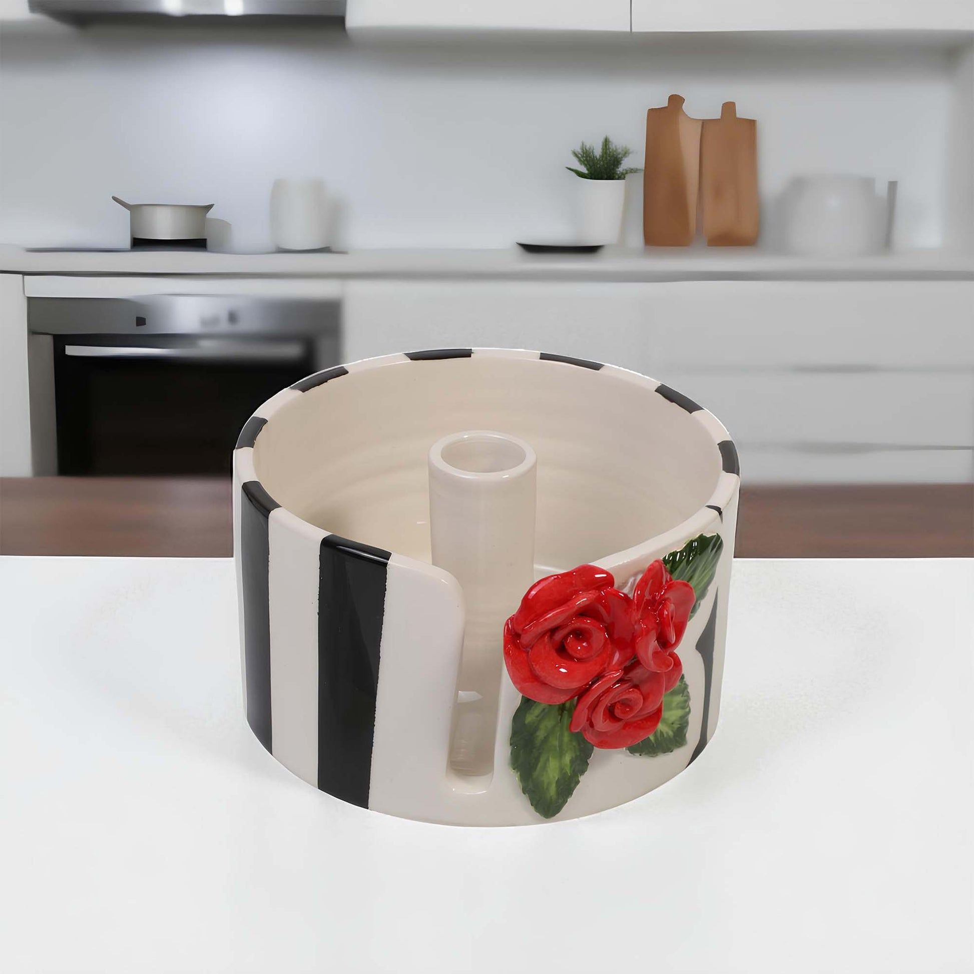 Decorative ceramic paper towel holder with red roses on a kitchen counter