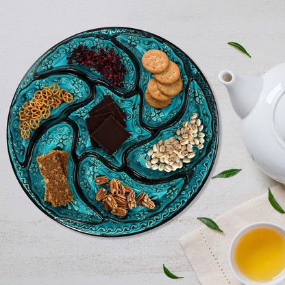 Decorative snack serving tray setwith assorted snacks on a white surface with a teapot and cup of tea.