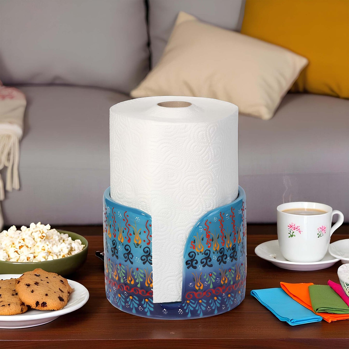 Roll of paper towels in a decorative paper towel holder on a table with snacks and coffee.