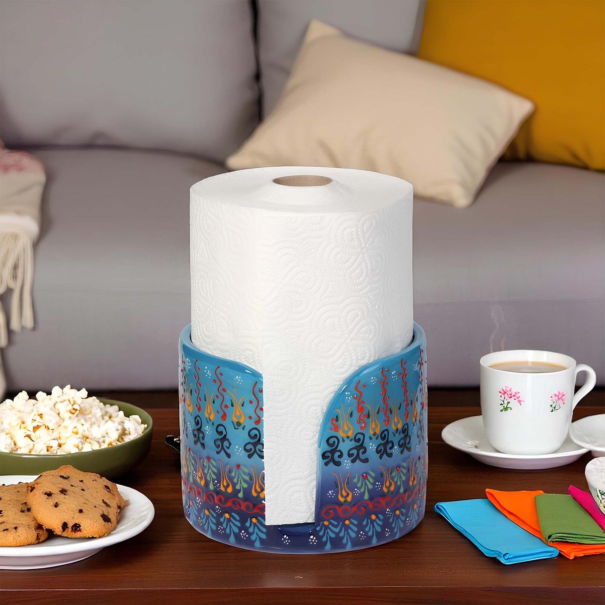 Roll of paper towels in a decorative paper towel holder on a table with snacks and coffee.