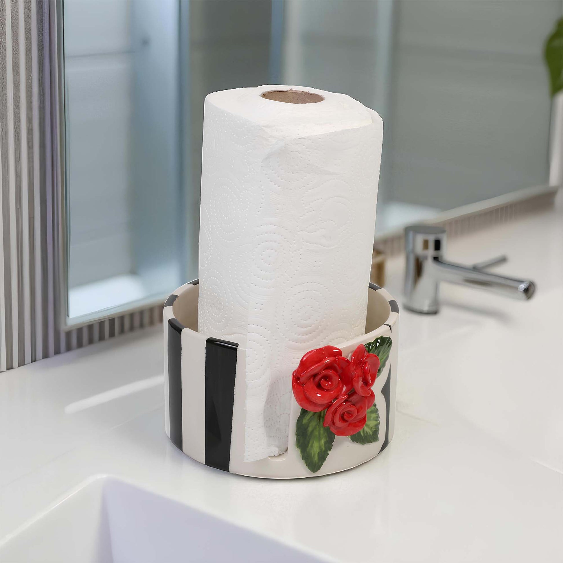 Roll of paper towels in a decorative paper towel holder with red roses on a kitchen counter.