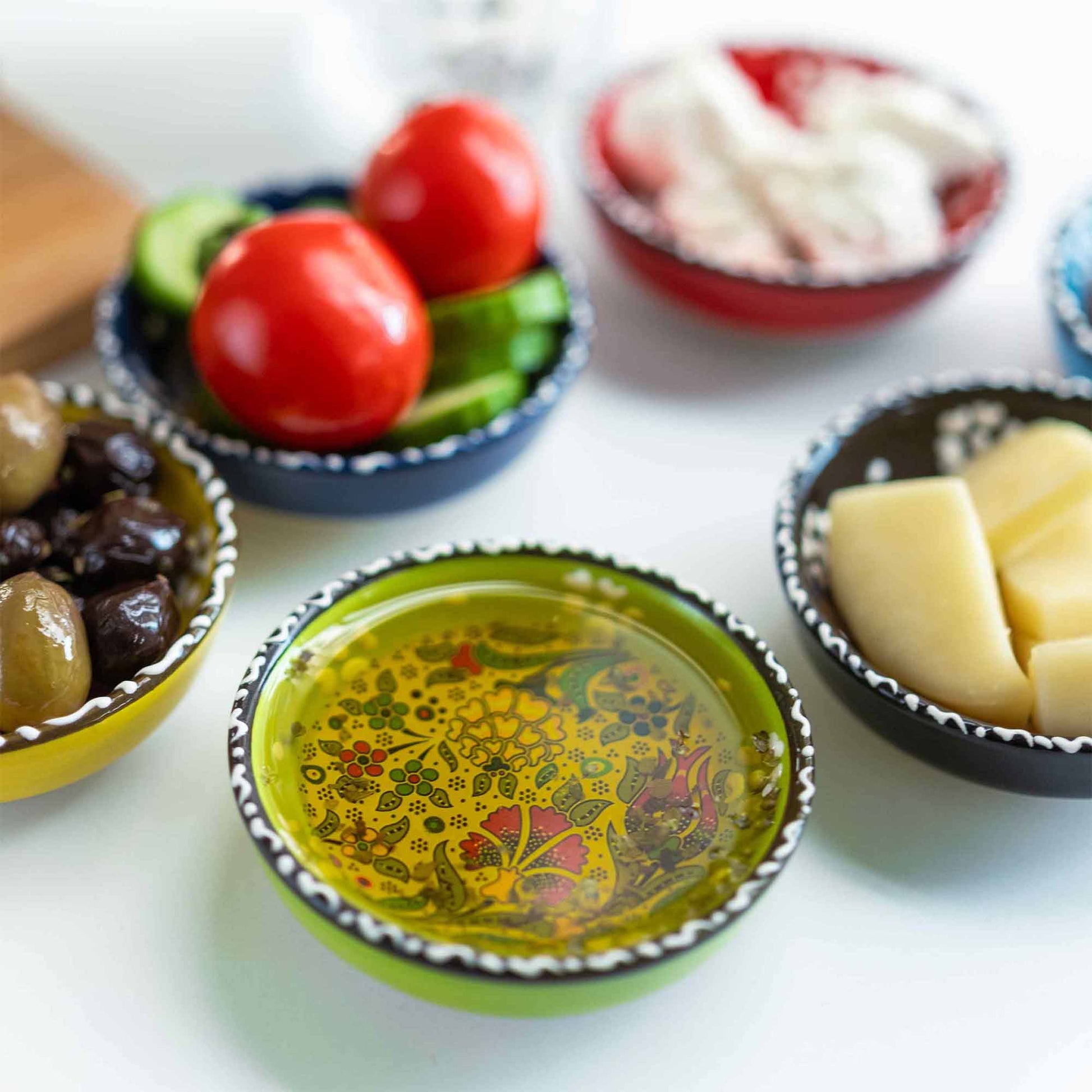 Assorted food items on small decorative sauce bowls on a white surface