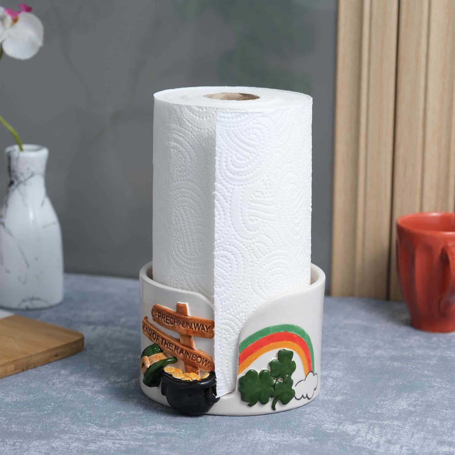 Decorative paper towel holder with a roll of paper towels on a table.