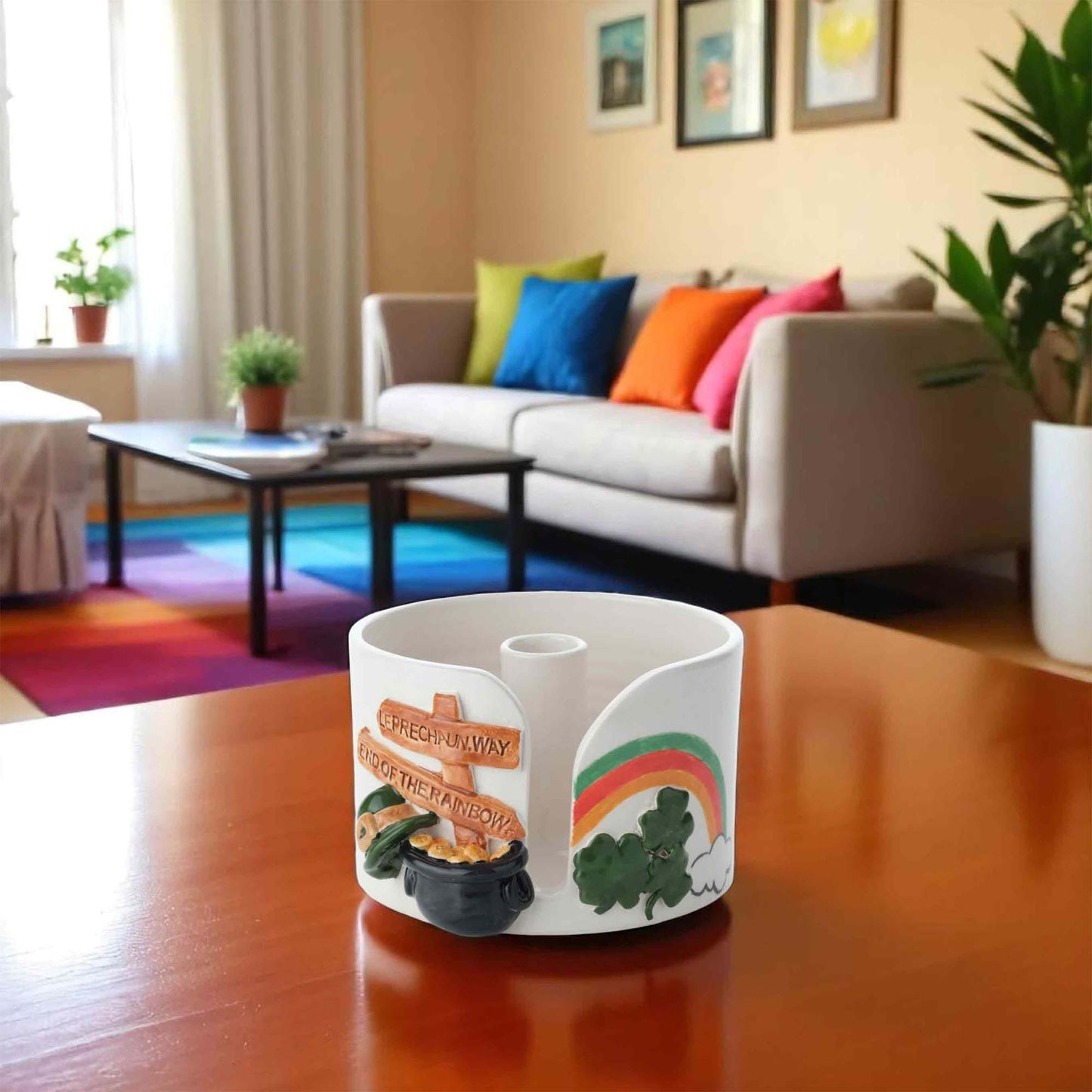 Decorative paper towel holder with rainbow and pot of gold design on a wooden table in a living room.