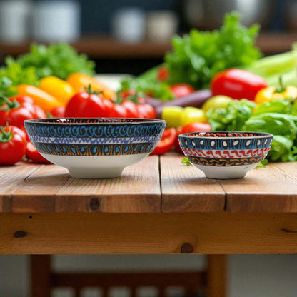 Two decorative ceramic bowls on a wooden table with vegetables in the background