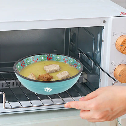 Person placing a bowl of soup with croutons into an open microwave.
