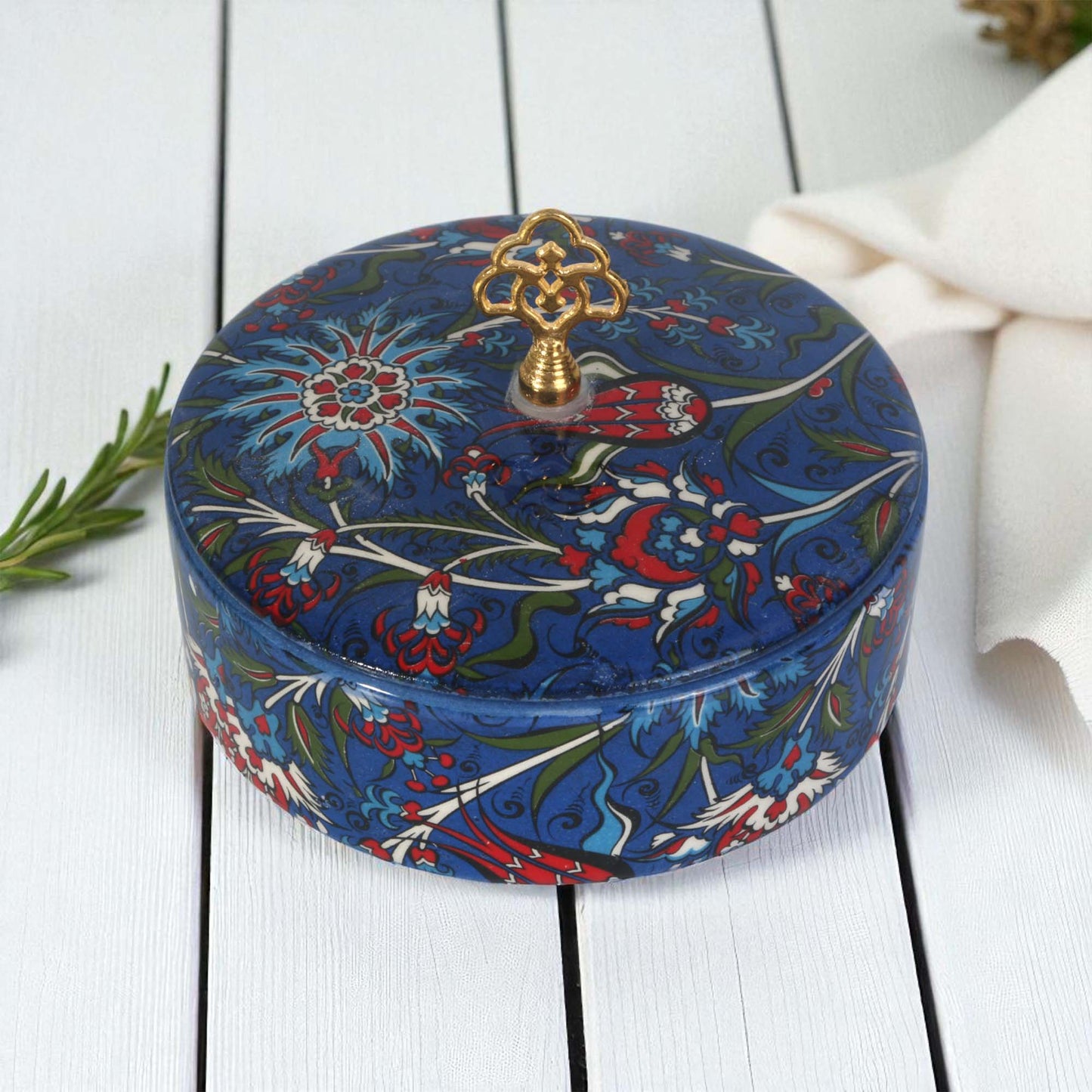 Decorative blue sugar bowl with floral patterns on a white wooden surface