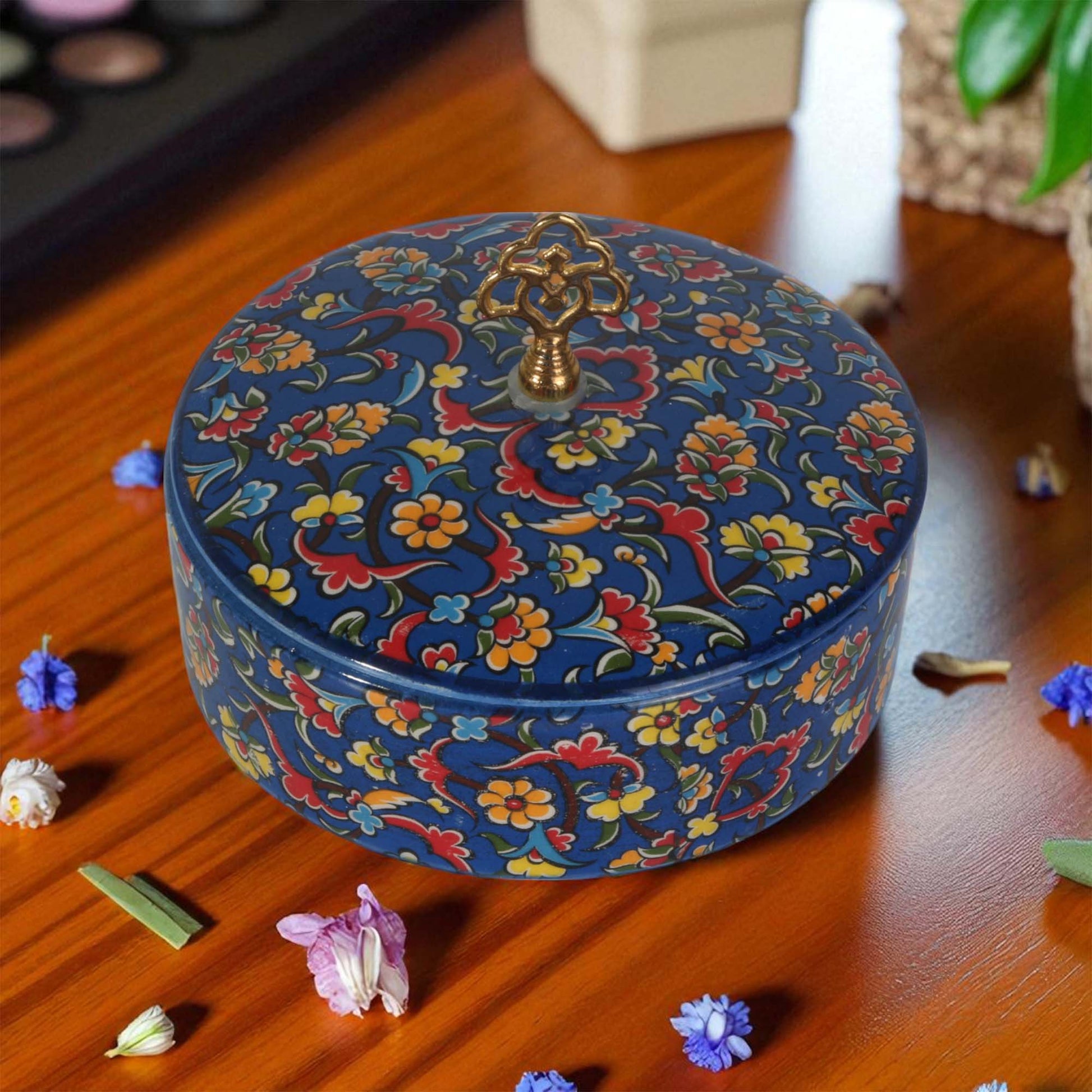 Decorative sugar bowl with floral patterns on a wooden surface with flowers around