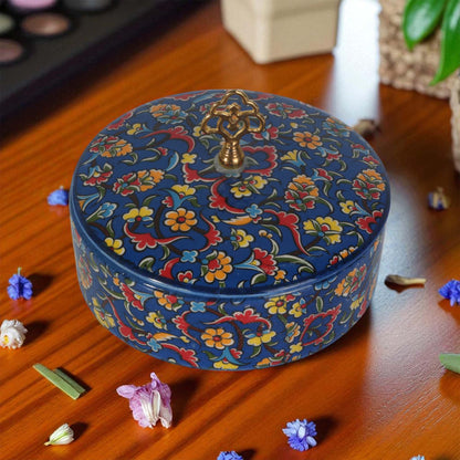 Decorative sugar bowl with floral patterns on a wooden surface with flowers around