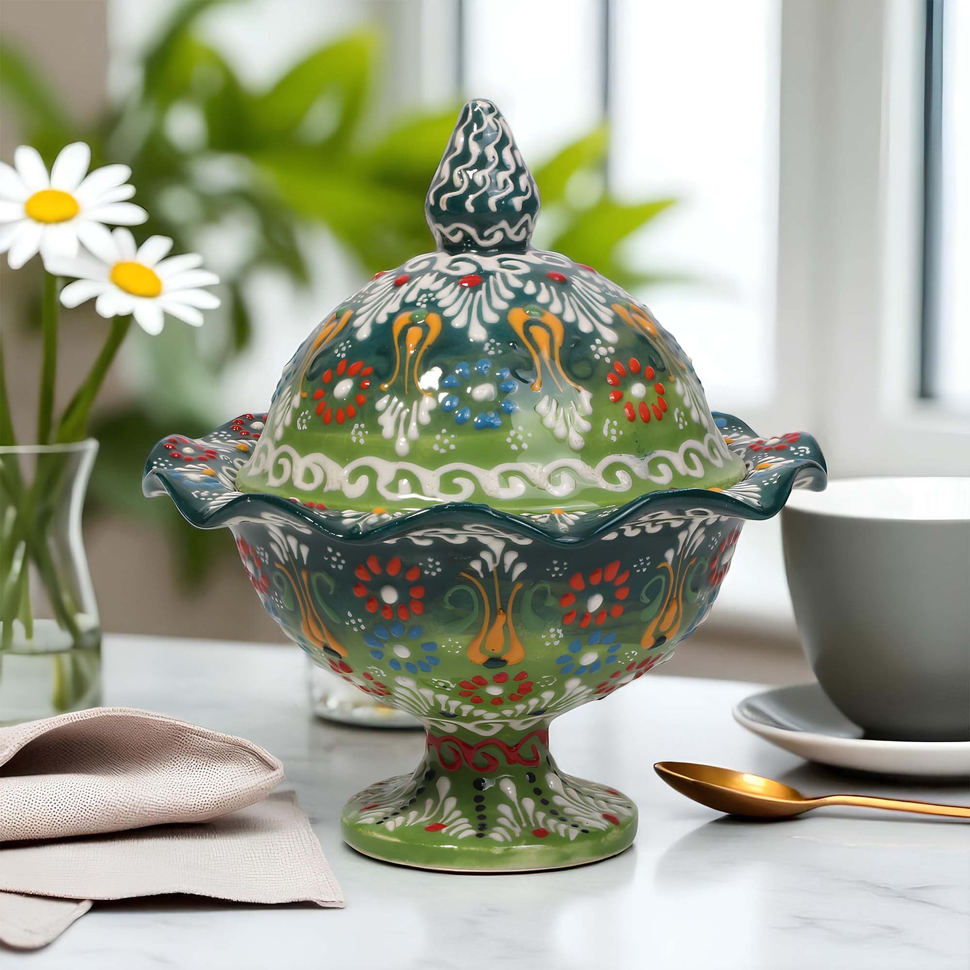 Decorative ceramic sugar bowl with floral patterns on a table with a cup and spoon.