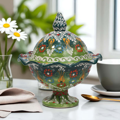 Decorative ceramic sugar bowl with floral patterns on a table with a cup and spoon.