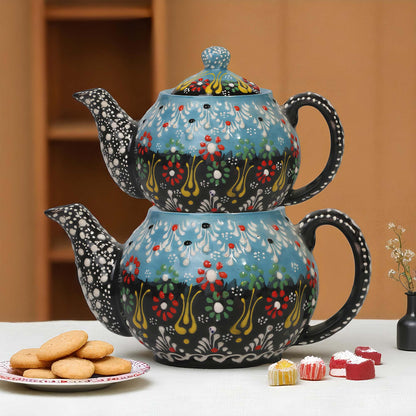 Decorative teapot with floral patterns on a table with cookies and candies.