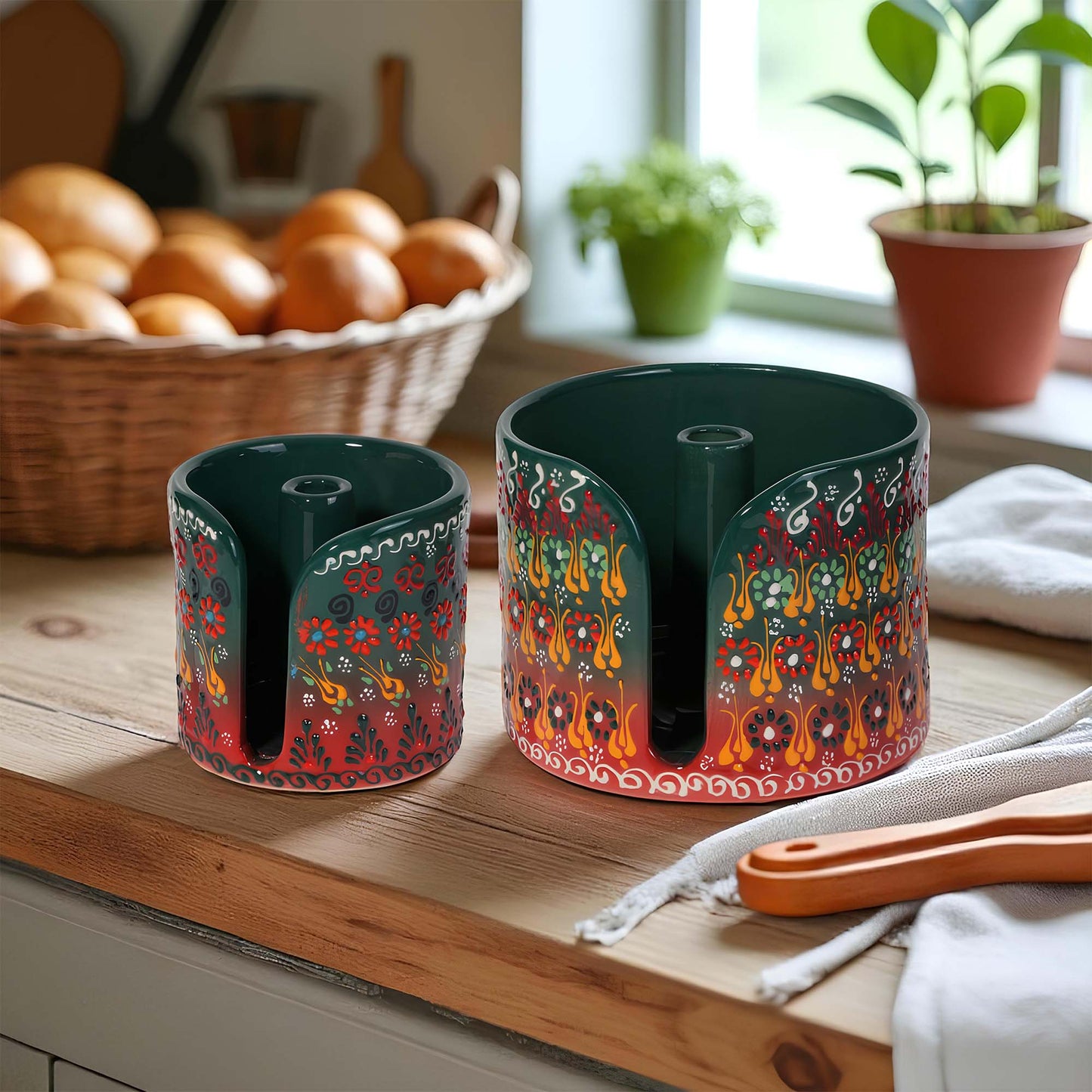 Two decorative ceramic paper towel holders on a wooden surface with a kitchen background.