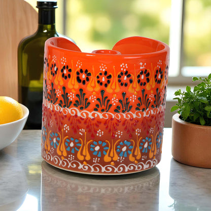 Decorative orange ceramic paper towel holder with floral patterns on a table.