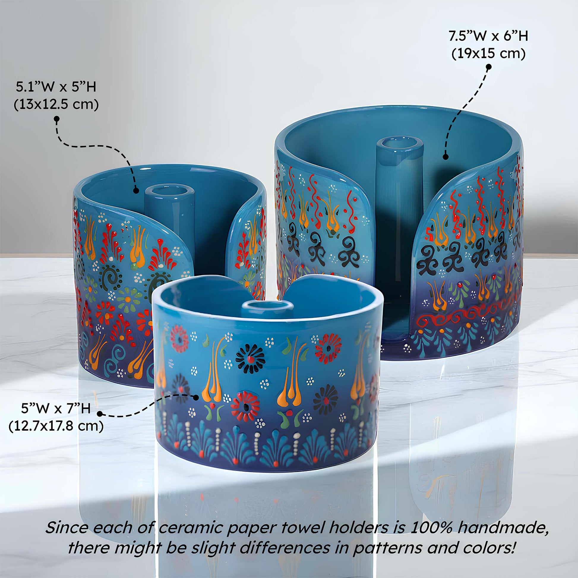 Three blue ceramic paper towel holders with floral patterns on a white background, showing measurements and text about handmade nature.