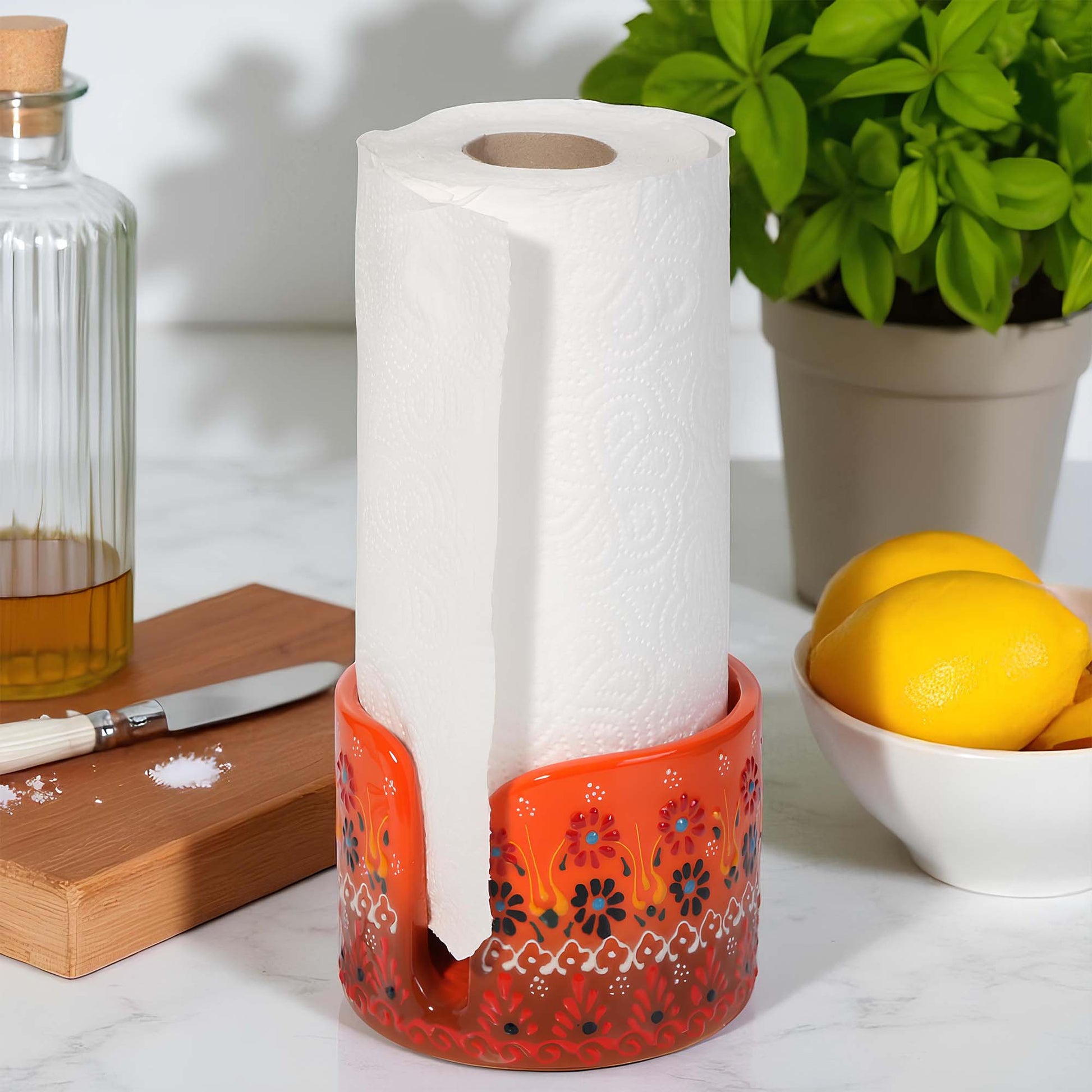 Decorative paper towel holder with a roll of paper towel on a kitchen counter with lemons and a plant.