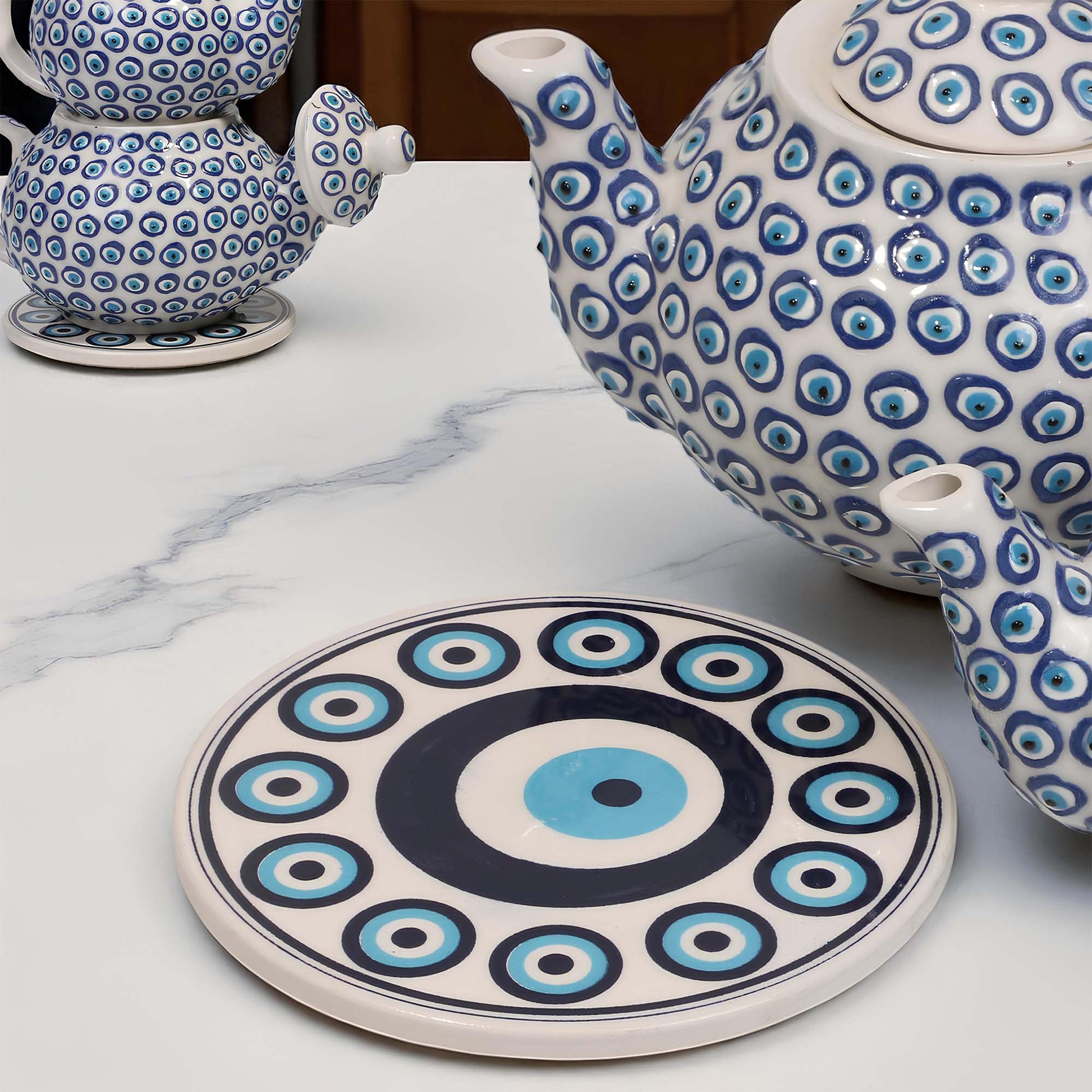 Ceramic teapot and trivet with blue and white pattern on a marble surface