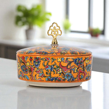 Decorative ceramic sugar bowl with floral patterns and a gold lid on a white surface.