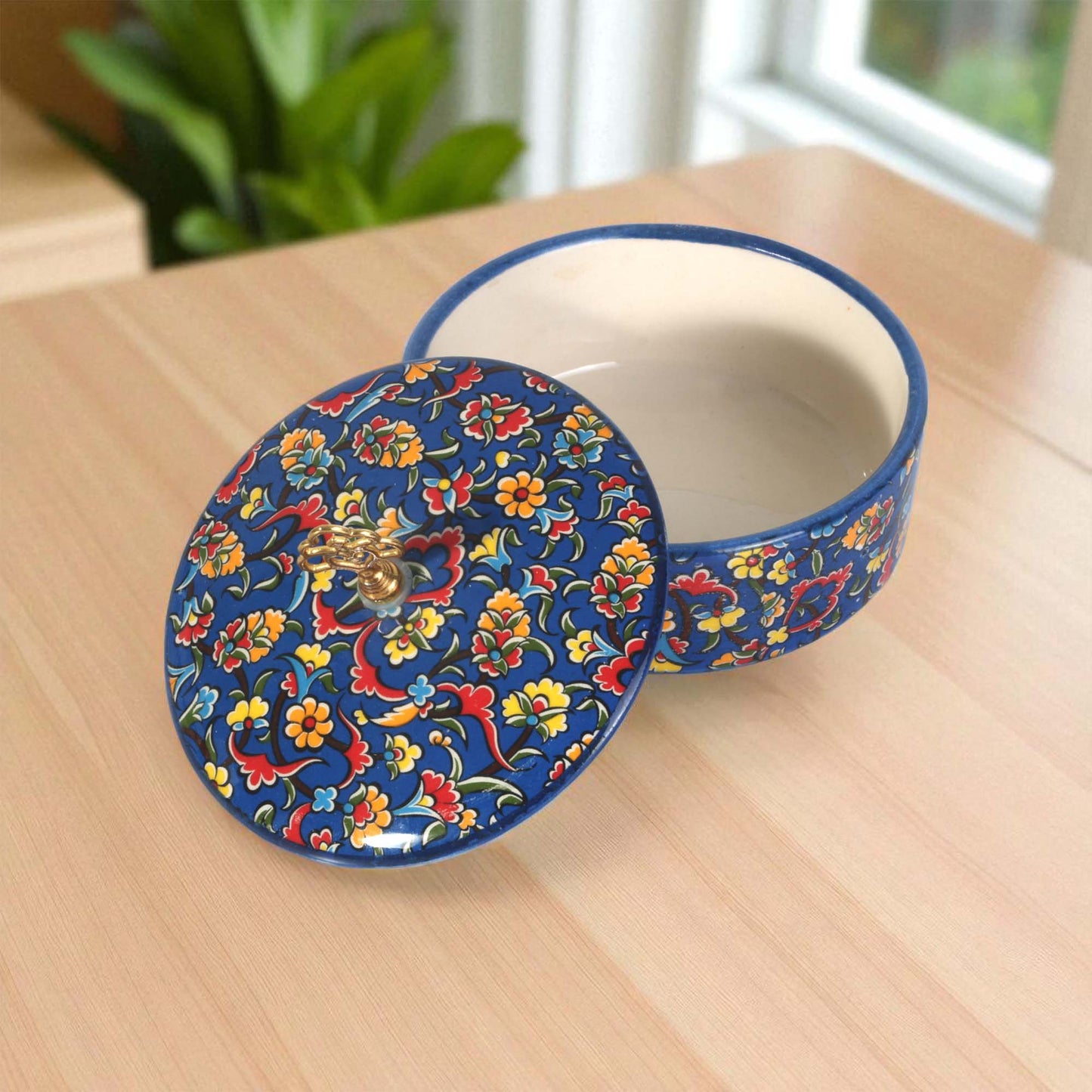 Decorative ceramic sugar bowl with floral design on a wooden surface