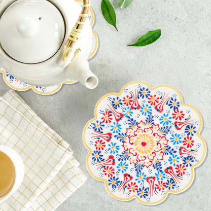 Decorative floral trivet on a table with a teapot and cup.