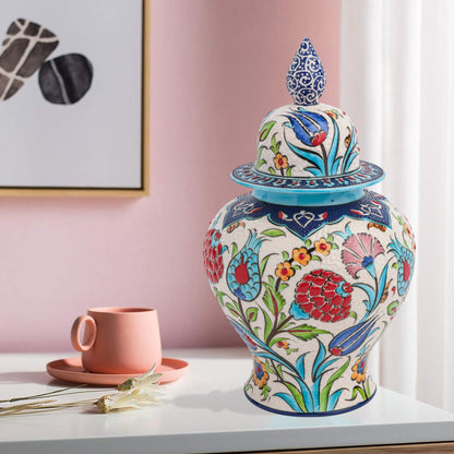 Hand-painted Floral Festival ceramic jar with red carnations, blue tulips & yellow blossoms. Glossy artisan jar with cobalt finial lid, perfect décor or gift.