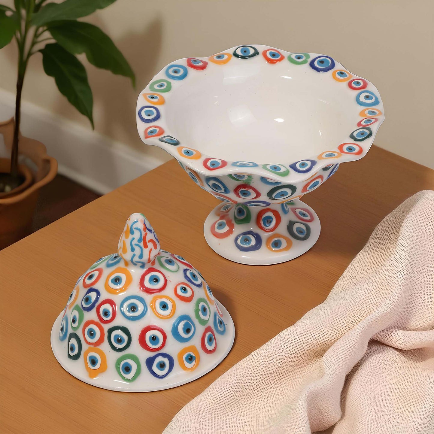Ceramic sugar bowlwith colorful circular patterns on a wooden surface.