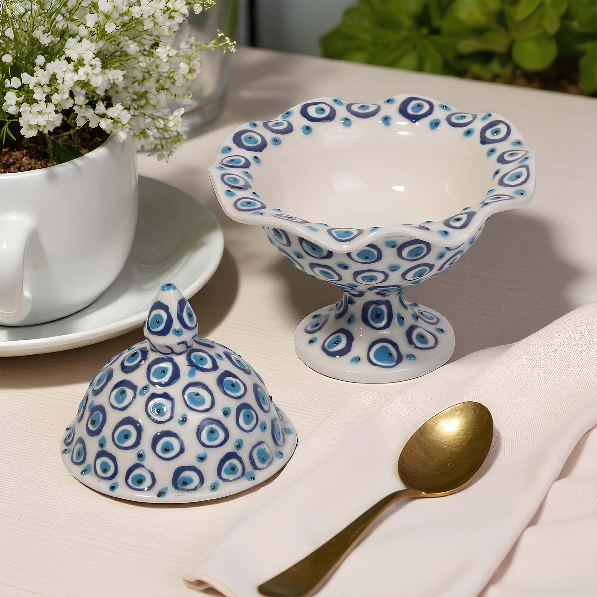 Ceramic sugar bowl with blue and white pattern on a table with a cup, saucer, and gold spoon.
