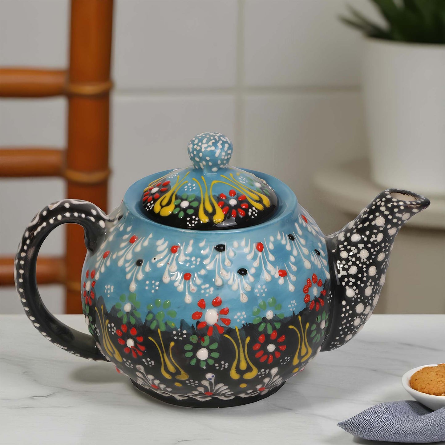 Decorative ceramic teapot with floral patterns on a white surface.