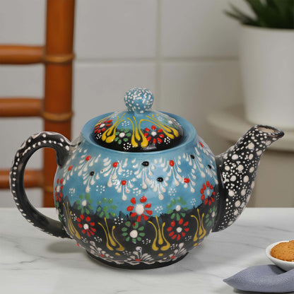 Decorative ceramic teapot with floral patterns on a white surface.