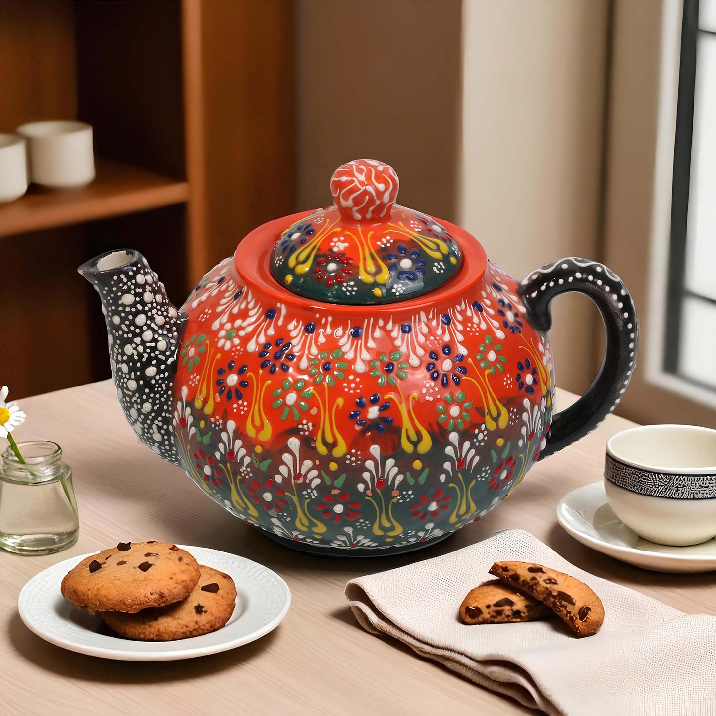 Colorful ceramic teapot on a table with cookies and tea.