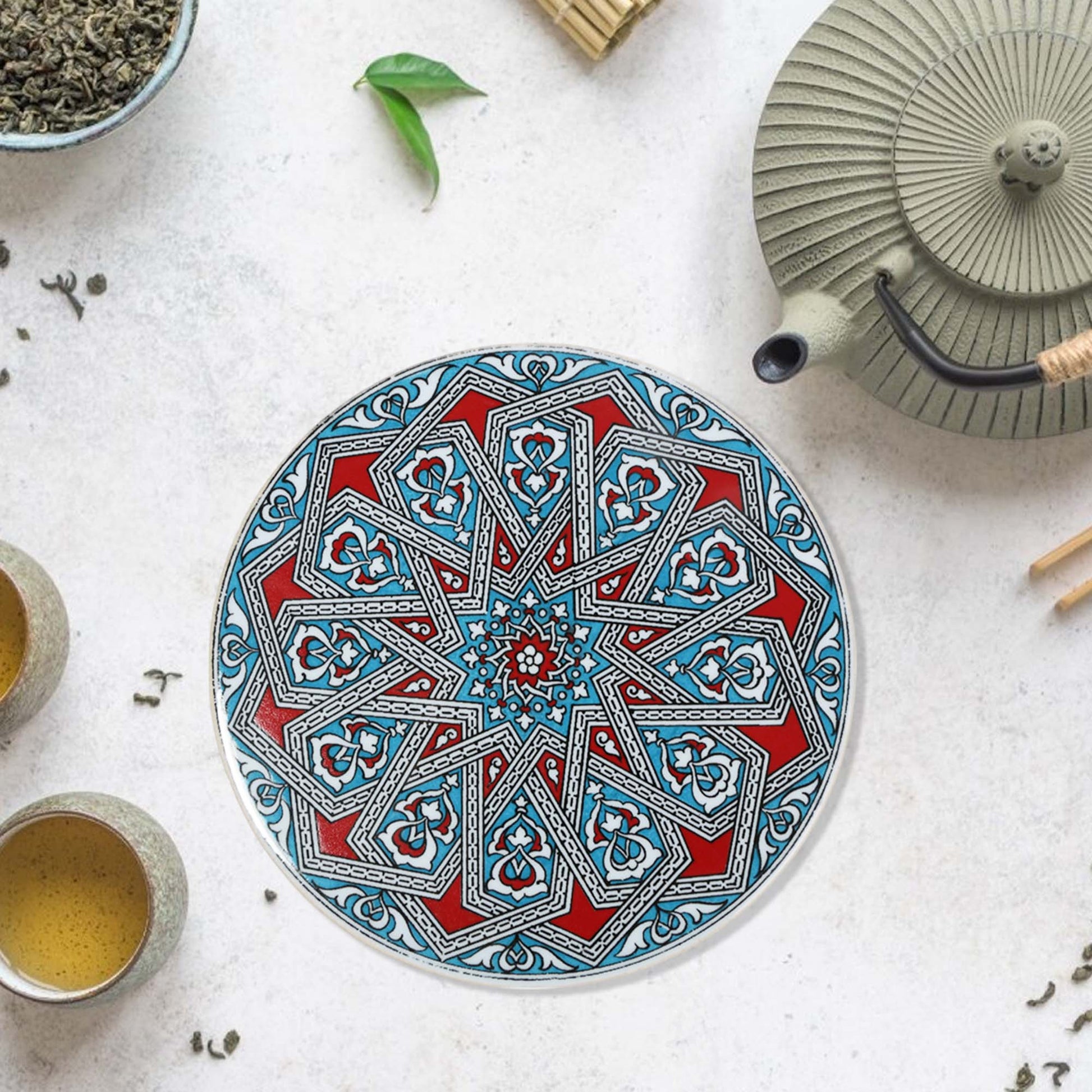 Decorative trivet with geometric pattern on a white surface with tea-making items.