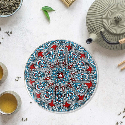 Decorative trivet with geometric pattern on a white surface with tea-making items.