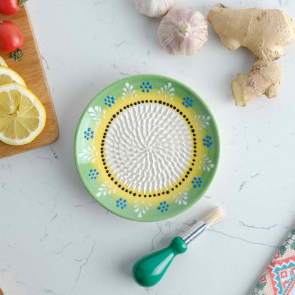 Decorative ceramic garlic grater plate  with a brush and ingredients on a light surface
